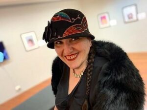 guler altunbas artist displays her work at local cafe, smiling in front of her artwork