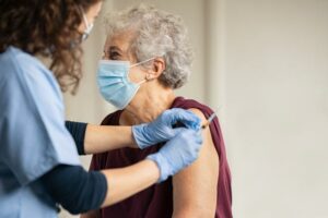 nurse with older female patient, getting a COVID-19 booster