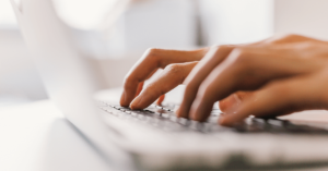An unidentified general practitioner types at their laptop