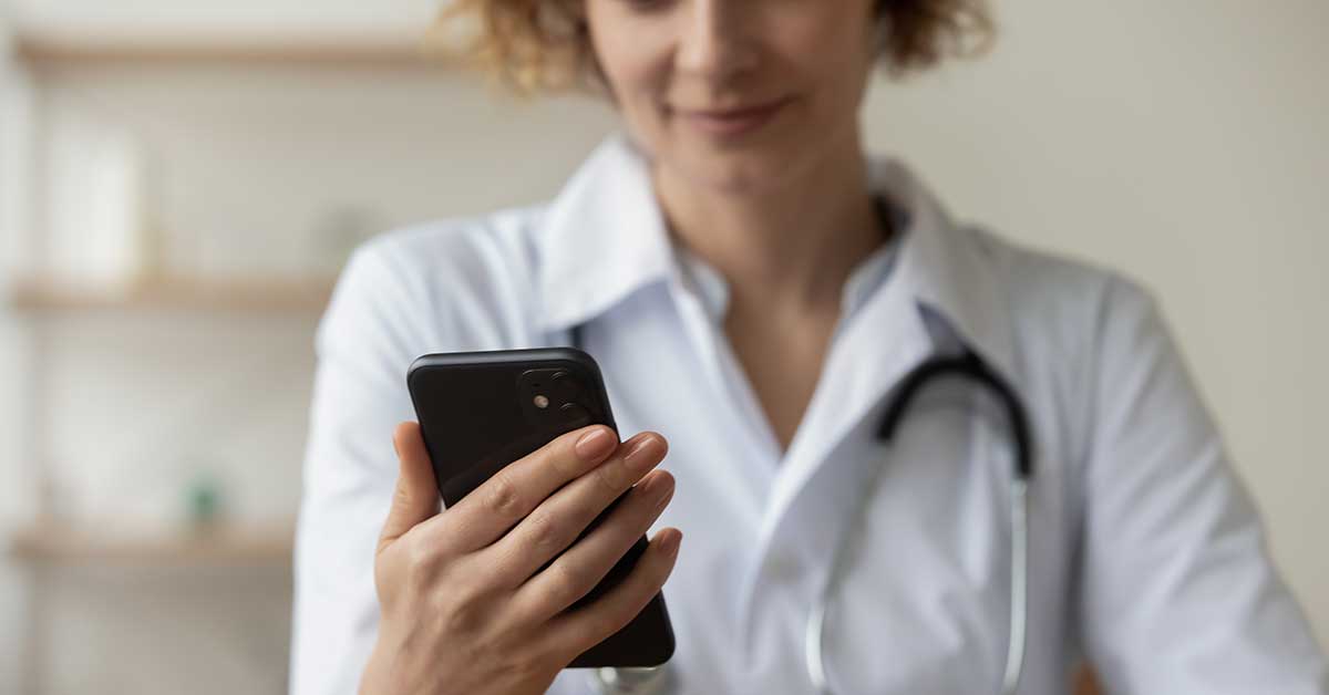 A GP uses her mobile phone to contact the family violence secondary consult service