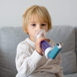 A child uses an asthma inhaler with spacer at home